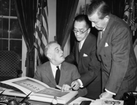 1941年10月10日,中国驻美大使胡适博士(中)向美国总统罗斯福(左)解说含有中国一万师生签名的书册