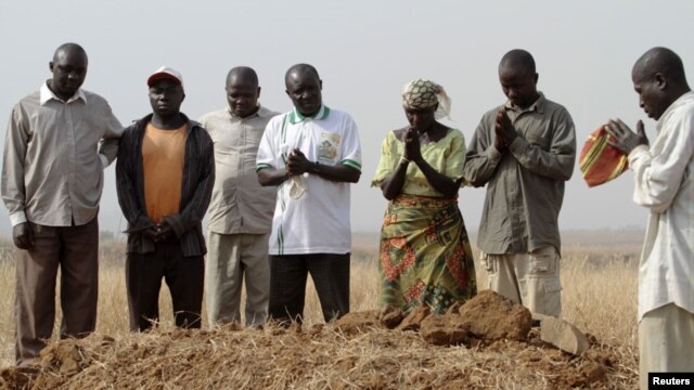 A family gathers around the grave, where three murdered family members were buried together, in Jos in Nigeria's Plateau state, December 28, 2011. Armed Fulani herdsmen shot dead three members of a family in an attack in Nigeria's ethnically and religious