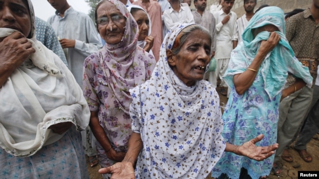 Women grieve and wait outside a building for their relatives after a fire at a garment factory in Karachi September 12, 2012.  