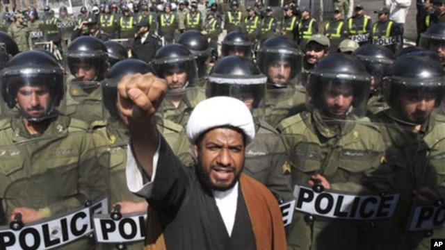 A Bahraini Shi'ite cleric chants slogans in a protest against Saudi and Bahraini leaders in front of the Saudi Embassy in Tehran, as Iranian police officers protect the Embassy, Iran, March 17, 2011