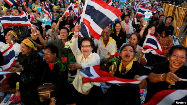 Protesters wave Thai national flags as their leaders appear on stage during a protest in central Bangkok on November 1, 2013.