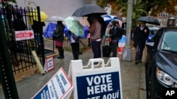Los votantes se alinean bajo la lluvia en las afueras de Bright Family and Youth Center en el vecindario de Columbia Heights en Washington, el martes 6 de noviembre de 2018.