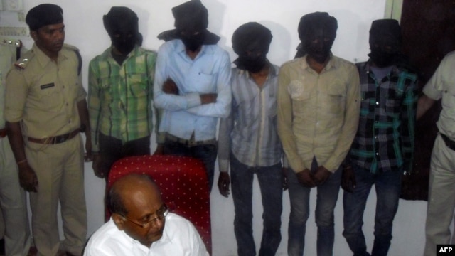 Indian Deputy Inspector General DK Arya (C) sits in front of five hooded suspects during a press meeting in Datia, about 75 kms from Gwalior in central Madhya Pradesh state, March 17, 2013. 