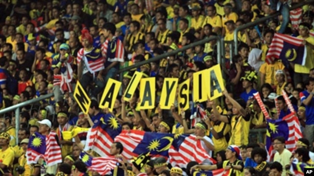 Malaysia football fans hold up national flags during the AFF Cup 2010 first leg finals football final match held at the Bukit Jalil National Stadium in Kuala Lumpur, Dec. 26, 2010.