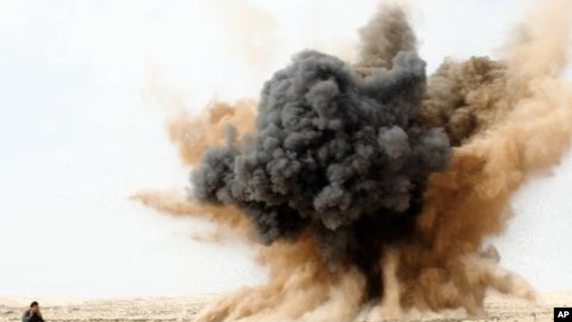 A rebel holds his ears as a bomb launched by a Libyan air force jet loyal to Libya's leader Muammar Gaddafi explodes in the desert near Brega, March 2, 2011