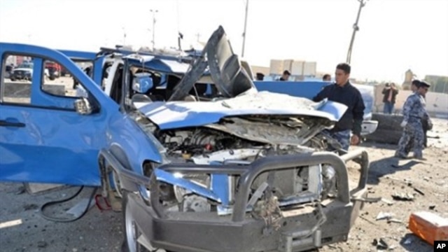 A policeman looks at a damaged police vehicle following a car bomb and minutes later a suicide bombing targeting the provincial headquarters in the western Iraqi city of Ramadi, 27 Dec, 2010.