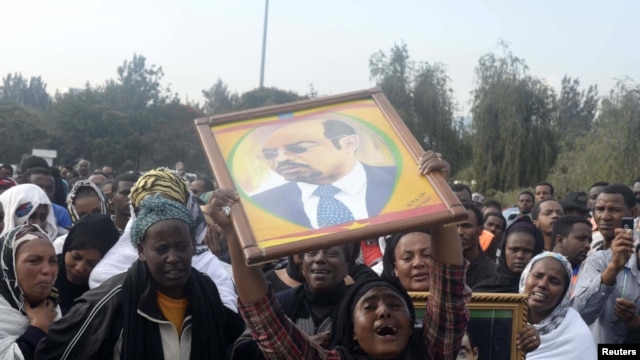 A woman wails while lifting a portrait of Ethiopia's PM Meles Zenawi as she waits for the arrival of his remains in Ethiopia's capital Addis Ababa, August 21, 2012.