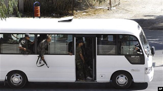 In this citizen journalism image, Syrian security forces lean out of a bus windows as they withdraw from the Damascus suburb of Saqba, Syria,  following a campaign of raids and arrests that are part of a nationwide crackdown against protesters calling for
