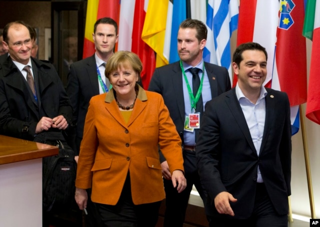 Greek Prime Minister Alexis Tsipras, right, walks with German Chancellor Angela Merkel, center, as they leave an EU summit in Brussels, March 8, 2016.