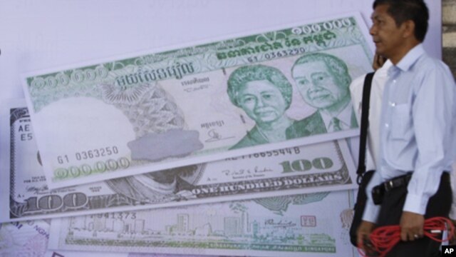 Cambodian men hang out by a currency poster during the inauguration ceremony of the Cambodia Securities Exchange in Phnom Penh, file photo. 