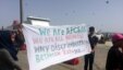 Travelers from Afghanistan hold up a sign in protest of claims that they are "economic migrants," rather than people who fled what some see as legitimate dangers before they have even applied for asylum in Athens, Greece, on April, 8, 2016. (H. Murdock / 