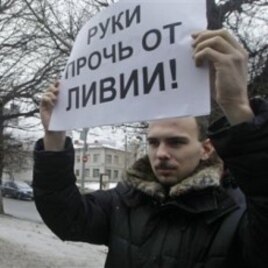 An activist of an anti-Kremlin opposition group, The Left Front, holds a poster reading 'Hands off Libya' during his picket at the NATO representative office in Moscow, Russia, March 19, 2011