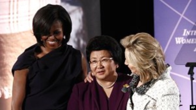 U.S. first lady Michelle Obama (L) and Secretary of State Hillary Clinton (R) honor Kyrgyzstan President Roza Otunbayeva during the International Women of Courage Awards Ceremony at the State Department, March 8, 2011