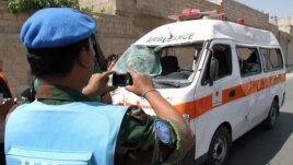 A UN observer photographs an ambulance that was destroyed after a car bomb exploded near the shrine of Sayyida Zeinab, in a suburb of Damascus, Syria, June 14, 2012.