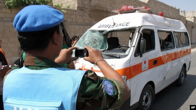A UN observer photographs an ambulance that was destroyed after a car bomb exploded near the shrine of Sayyida Zeinab, in a suburb of Damascus, Syria, June 14, 2012.