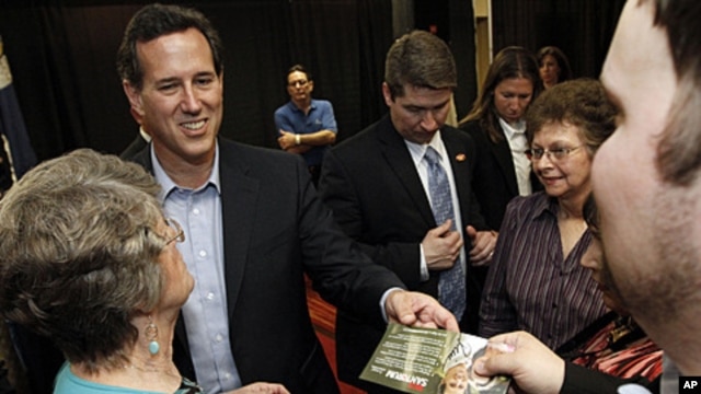 Republican presidential candidate former Pennsylvania Sen. Rick Santorum hands back an autographed campaign flyer at a rally in Shreveport, Louisiana, March 23, 2012. 