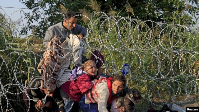 FILE - Syrian migrants cross under a fence into Hungary at the border with Serbia, near Roszke, August 2015.