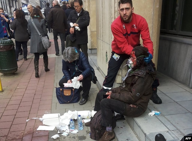 Nhân viên an ninh giúp một phụ nữ bị thương bên ngoài trạm xe điện ngầm Maalbeek ở Brussels, ngày 22/3/2016.