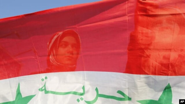 Syrian protesters stand behind a Syrian flag during a demonstration against Syria's President Bashar Al-Assad in front of the Syrian embassy in Amman, July 21, 2011