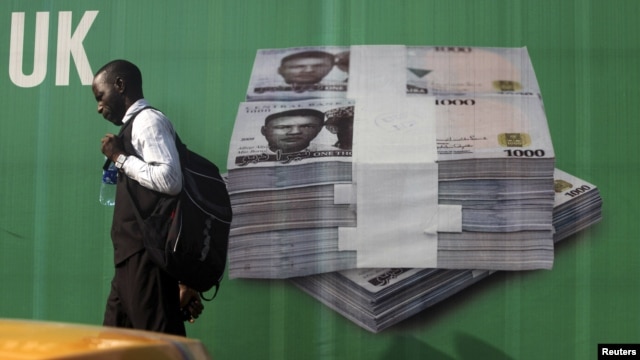 A man walks past a promotional banner showing a photograph of a pile of Nigerian naira along a road in Lagos November 24, 2010.