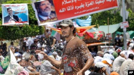 A volunteer sprays cold water on supporters of Egypt&#39;s ousted President Mohammed Morsi to overcome heat during a rally near Cairo University, where protesters have installed their camp in Giza, southwest of Cairo, Egypt, July 12, 2013. 
