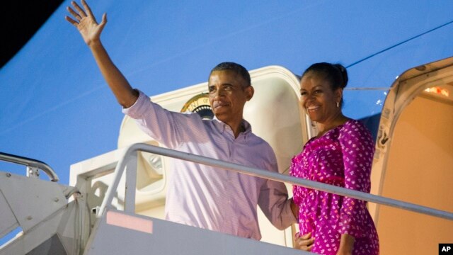 President Barack Obama, left, and first lady Michelle Obama wave as they board Air Force One to depart from Joint Base Pearl Harbor-Hickam at the end of their family vacation, Jan. 2, 2016, in Honolulu, Hawaii.