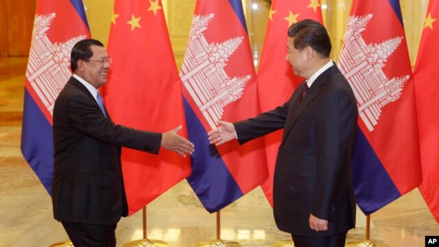 Cambodia's Prime Minister Hun Sen (L) stretches to shake hands with China's President Xi Jinping before a meeting at the Great Hall of the People in Beijing, November 7, 2014. REUTERS/Jason Lee/POOL