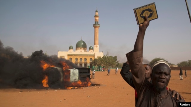 A man holds a copy of the Quran during a protest against Niger President Mahamadou Issoufou's attendance last week at a Paris rally in support of French satirical weekly Charlie Hebdo, in Niamey, Jan. 17, 2015.