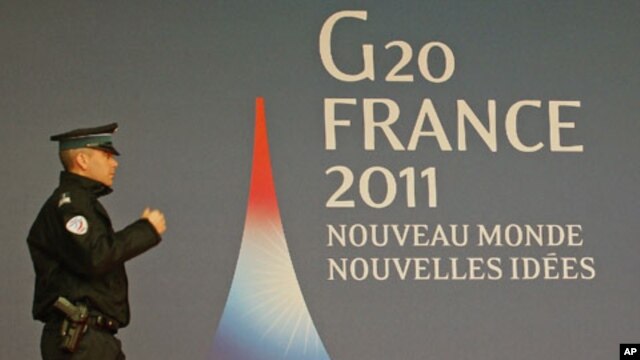 A French police officer walks past the G20 logo and slogan, 'New World, New Ideas,' outside the festival palace as preparations for the G20 summit continue in Cannes, France, November 2, 2011.