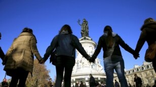 FILE - People hold hands to form a human solidarity chain near the site of the attack at the Bataclan concert hall in Paris, Nov. 15, 2015. 