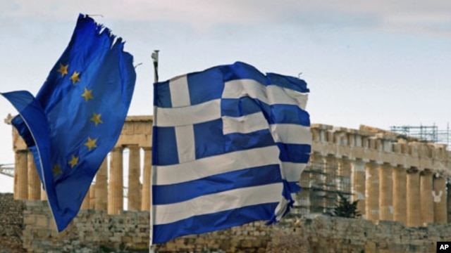 The Parthenon on the Athens Acropolis is seen behind a Greek and an EU flag atop the Greek ministry of finance, February 8, 2012.
