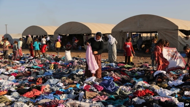 عراقی های ایزدی، در کمپ نوروز در سوریه، به دنبال لباس های مناسب برای خود که یک گروه خیریه فراهم کرده است