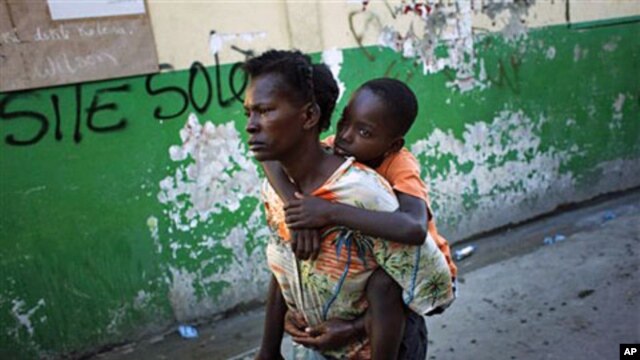 A boy suffering cholera symptoms is carried by a relative to St. Catherine hospital in Cite Soleil  slum in Port-au-Prince, 18 Nov 2010