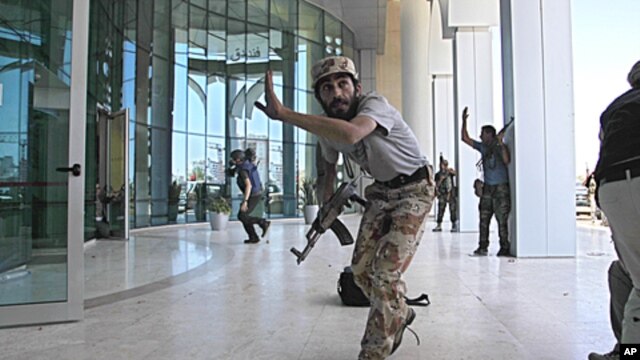 Rebel fighters and a television cameraman take shelter as an intense gun battle erupted outside the Corinthia hotel, where many foreign journalists are staying, in Tripoli, Libya, August 25, 2011