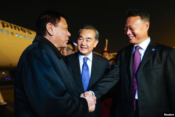 President of the Philippines Rodrigo Duterte (L) shakes hands with Chinese ambassador to the Philippines Zhao Jianhua (R), as Chinese Foreign Minister Wang Yi (C) looks on, at airport in Beijing, Oct. 18, 2016.