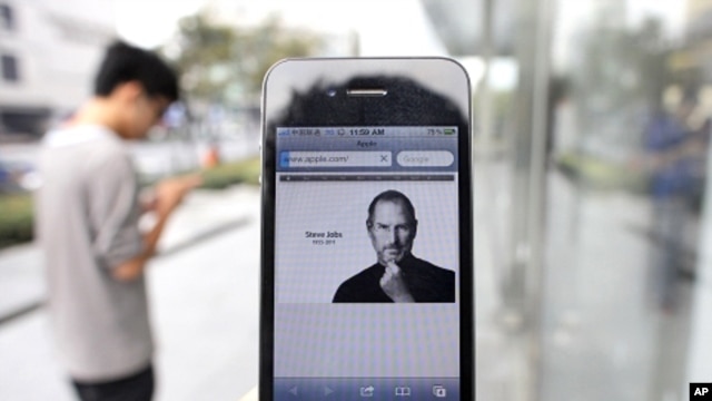 A man holds an iPhone 4 displaying an obituary of Apple co-founder Steve Jobs outside an Apple Store in downtown Shanghai October 6, 2011.