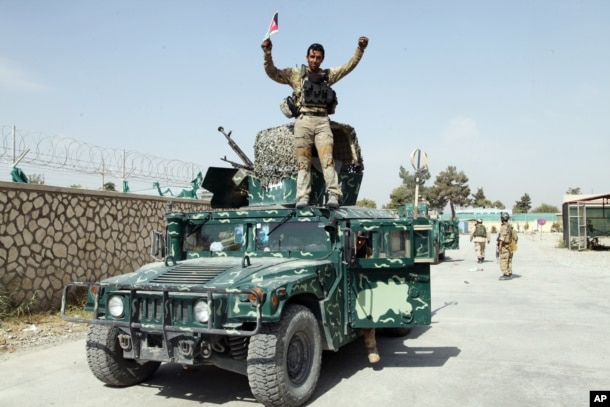 FILE - An Afghan soldier raises his hands as a victory sign, Oct. 2, 2015, in Kunduz city, north of Kabul, Afghanistan.