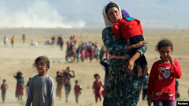 Displaced people from the minority Yazidi sect, fleeing violence from forces loyal to the Islamic State in Sinjar town, walk towards the Syrian border.