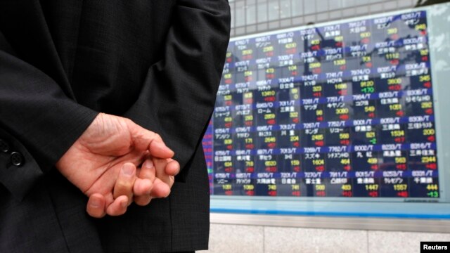 FILE - A man looks at a stock index board outside a brokerage, Tokyo, Japan, June 6, 2012.