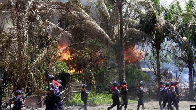 Policemen walk towards burning buildings in Sittwe, capital of Rakhine state in western Burma, where sectarian violence is ongoing, June 12, 2012. 