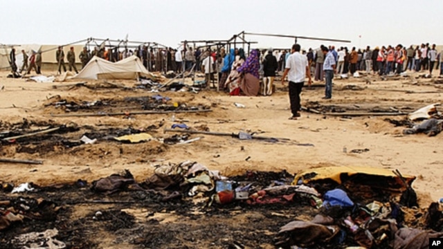 Refugees gather near burnt tents at Choucha camp in Tunisia near the Libyan border, May 22, 2011