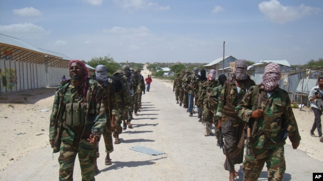 Members of Somalia's al- Shabab militant group patrol on foot on the outskirts of Mogadishu, March, 5, 2012.