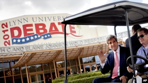 Sen. John Kerry, D-Mass., left, waves as he rides in a golf cart after giving an interview in front of the debate hall ahead of the presidential debate between Republican presidential candidate, former Massachusetts Gov. Mitt Romney and President Barack O