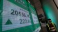 A man walks past an electronic board showing Hong Kong share index outside a local bank in Hong Kong, Jan. 8, 2016. 