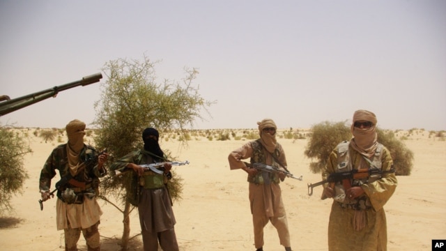 Fighters from Islamist group Ansar Dine stand guard during a hostage handover, in the desert outside Timbuktu, Mali, April 24, 2012.
