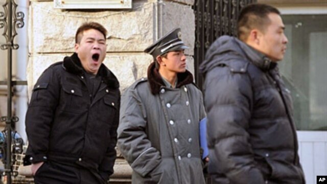 Plainclothes policemen (L and R) keep watch outside the house of jailed Chinese dissident Liu Xiaobo, the 2010 Nobel Peace Prize winner, in Beijing on 08 Dec 2010