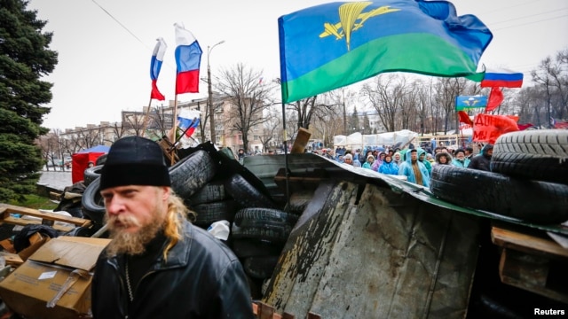 Pro-Russian supporters and an Orthodox priest (front) stand next to a barricade in front of the seized office of the SBU state security service in Luhansk, in eastern Ukraine on April 11, 2014. 