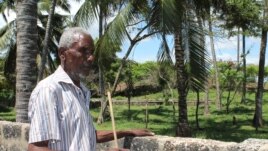 Piry Muye stands beside a stone wall fencing off the land that was once his, Mombasa, Kenya, November 18, 2012. (H. Heuler/VOA)