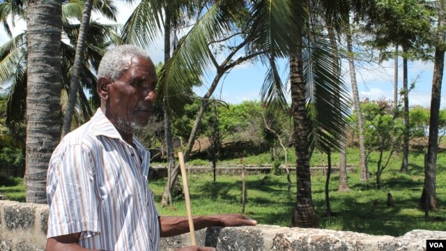Piry Muye stands beside a stone wall fencing off the land that was once his, Mombasa, Kenya, November 18, 2012. (H. Heuler/VOA)