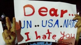In this citizen journalism image made and provided by the Kfar Suseh Coordinating of the Syrian Revolution on June 18, 2012, anti-Syrian regime protesters hold up a placard during a demonstration at Kfar Suseh area, in Damascus, Syria.